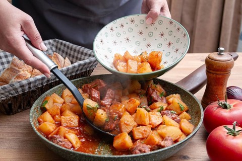 Homemade stew with potatoes and meat, cooked in a frying pan, is served on a plate