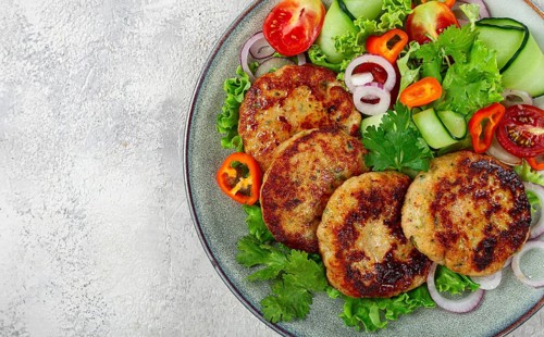 Fried chicken cutlets, minced chicken, with vegetables, on gray, with vegetable salad, top view,
