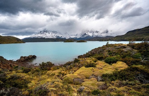 Cloudy mountain range Cuernos del Paine, shore of the blue lake Lago Pehoe in the evening light,