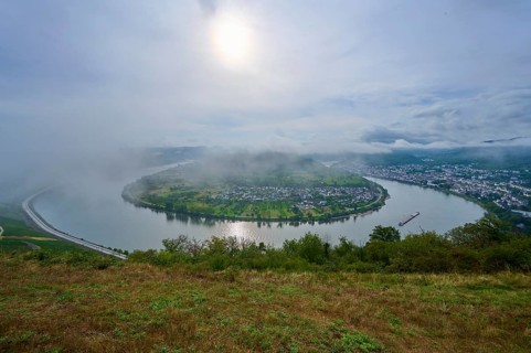 River bend under fog and with soft sunlight in the morning, surrounded by hills, summer, Rhine bend