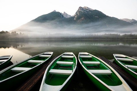 Magical sunrise with fog at Hintersee near Ramsau in Berchtesgadener Land. Boats in the foreground