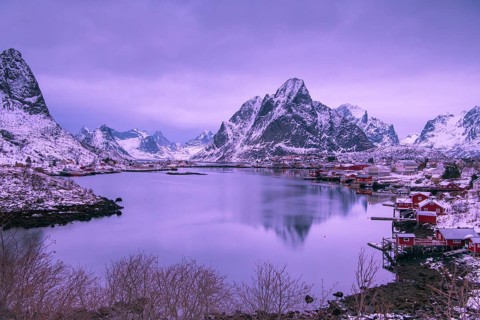 Fishermen's Village in front of snowy mountain range at the coastline in winter, Lofoten, Norway