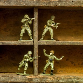 A set of classic plastic toy soldiers arranged on a wooden shelf, displaying soldiers in various