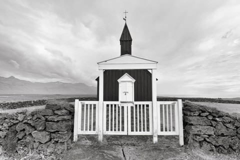 Traditional black church with white wooden door and stone wall, wooden church Budakirkja,