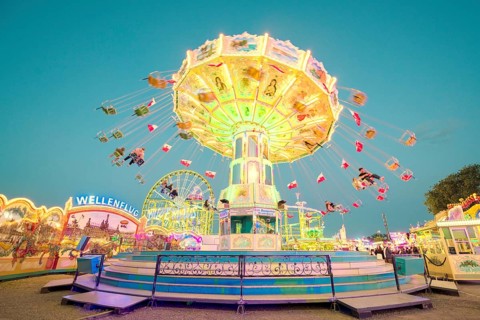 A brightly lit chain carousel turns at a daytime fair, Chain carousel, Spring festival, Cannstatter
