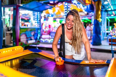 Happy tourist enjoying an exciting air hockey game in a vibrant luna park, experiencing fun and