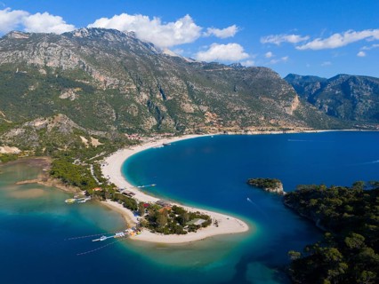 Aerial view of a picturesque coastline with sandy beach, mountains and clear water under a blue