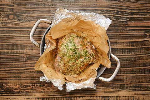 A perfectly roasted turkey thigh, seasoned with herbs and spices, rests on a bed of parchment paper