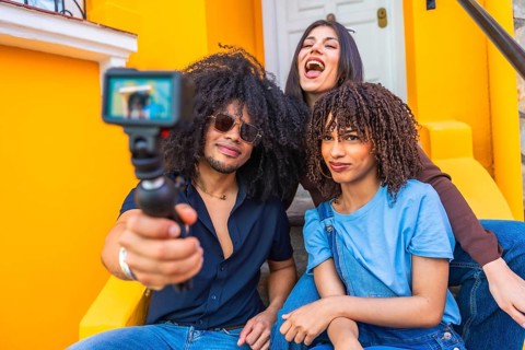 Three latin friends filming a vlog using a gimbal and action camera, enjoying laughter and smiles