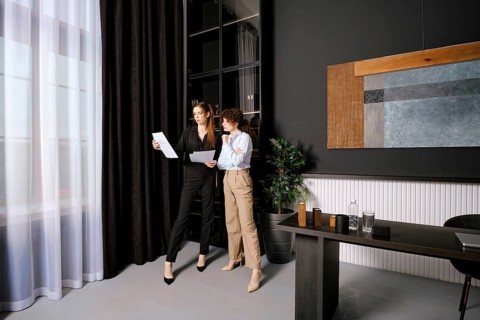Two businesswomen discussing documents in a modern office environment during the afternoon