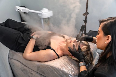 Beautician performing a facial hydration treatment using vapor, enhancing skin health and promoting
