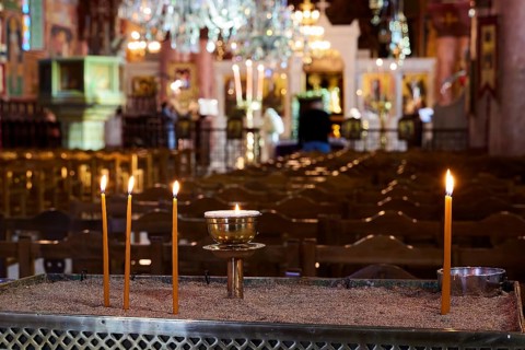 Burning candles on a sand container in an illuminated church with blurred surroundings, Church of