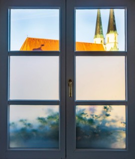 View through a closed window to the collegiate parish church of St Philip and St James, place of