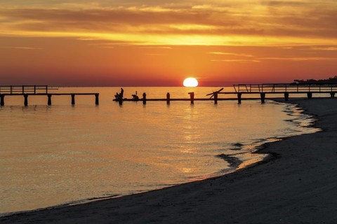 Sunset behind dilapidated fishing pier damaged by hurricanes on the Mississippi Gulf Coast in Long