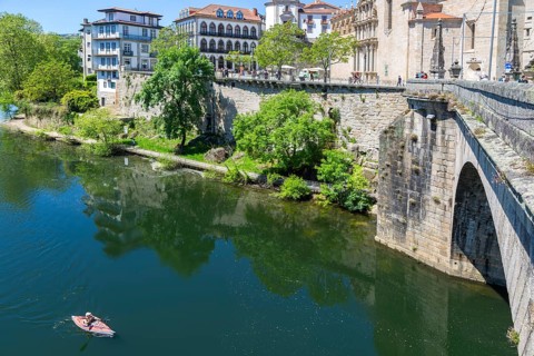 Person kayaking in River Tamega next to historic town centre, Amarante, Portugal