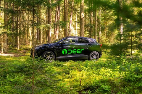 Black car with green stickers parked in a sunny forest, Deer E- Carsharing, Calw, Black Forest,
