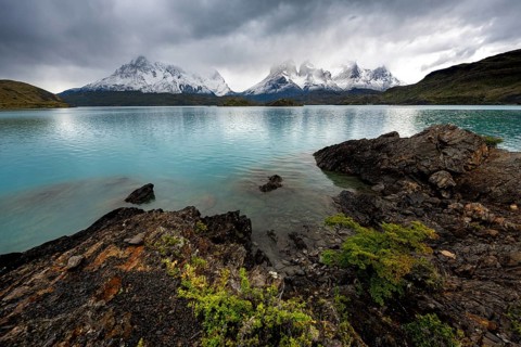Cloudy mountain range Cuernos del Paine, shore of the blue lake Lago Pehoe in the evening light,