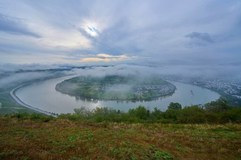 River bend under a cloudy sky and enveloping fog, gentle hills define the scenery, summer, Rhine