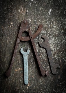 A collection of vintage tools, including a caliper and several wrenches, rests on a rustic wooden