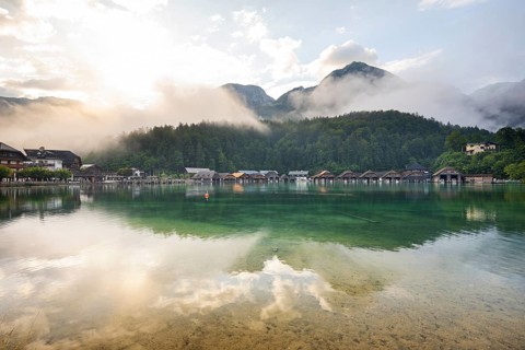 Mystical morning at Königssee in Schönau with boathouses. Sunrise and beautiful wafts of mist over