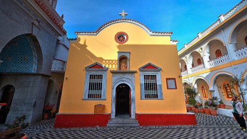 Yellow church with courtyard, cross and baroque elements, surrounded by plants, Holy Week, Bay of