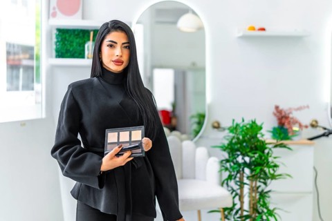 Professional makeup artist holding a palette and brush, offering makeup services in a modern and
