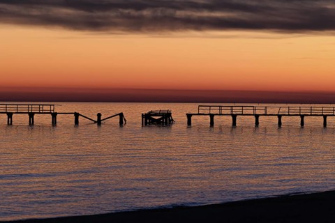 Sunset behind dilapidated fishing pier damaged by hurricanes on the Mississippi Gulf Coast in Long
