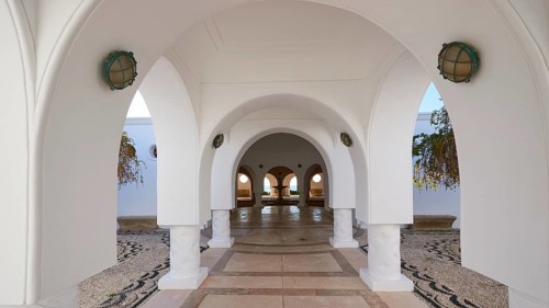 A tranquil area with white arches and hanging plants, framed by decorative arches and lights,