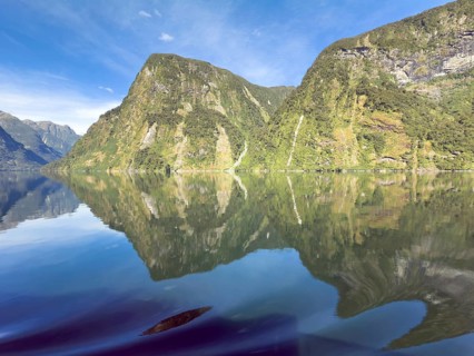 Mountains with reflections in the water against a blue sky in Doubtful Sound, South Island, New