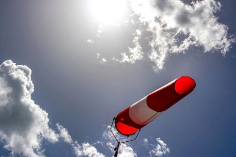 A colorful windsock hangs from a tall pole, clearly indicating wind direction. The bright sky is