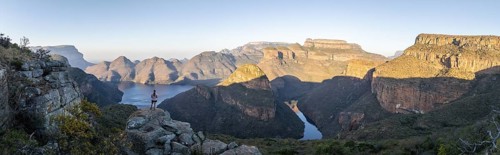 Hiker enjoying panorama, sunset at Blyde River Canyon with Three Rondawels peak, view of canyon