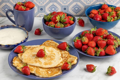 Pancakes with strawberries and yoghurt on blue crockery
