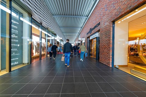 Visitors in the shopping centre surrounded by shops and modern architecture, Outlet City Metzingen,