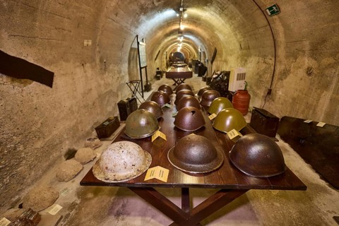 Table with various helmets in a long tunnel exhibition area, steel helmets, war museum, military