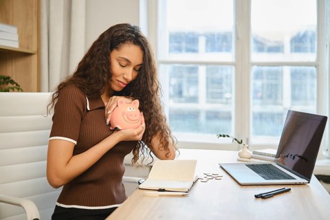A young woman hugs a piggy bank with love and rejoices that her decision to save money led to