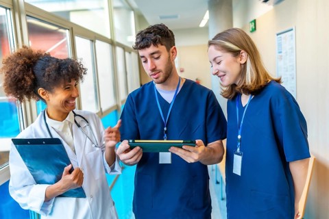 Doctors and nurses reviewing medical records on a tablet, collaborating on patient care in a