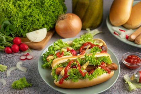 Hot dogs with ketchup, mustard, lettuce and radishes on a green plate