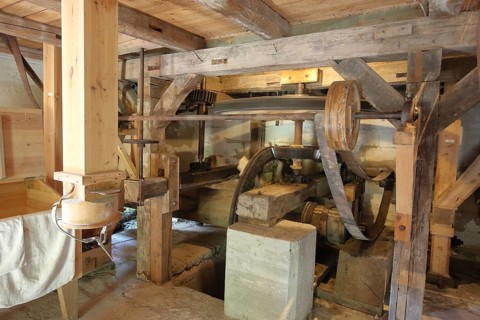 Interior view of mill, wooden construction, wooden beams, wheels, belt, drive wheel, flywheel,
