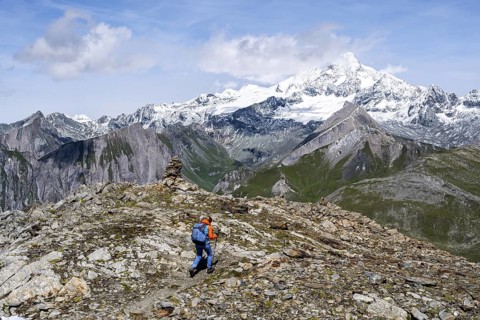 Mountaineer on a hiking trail, snow-covered and glaciated summit of the Großglockner in the