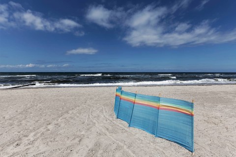 Deserted Baltic Sea beach with a single windbreak, blue sky, Kühlungsborn, Baltic Sea,