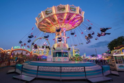 Colourfully illuminated carousel at a funfair in front of a night sky, chain carousel, spring