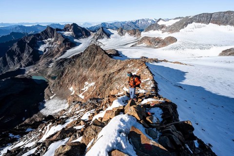 Mountaineer on a rocky ridge on the Wilder Freiger summit, behind him Signal summit and Becher