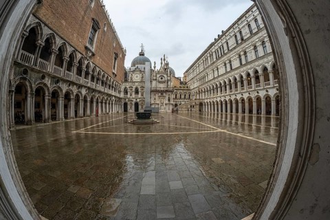 Wet pavement reflecting surrounding historical architecture in doge's palace courtyard on a rainy
