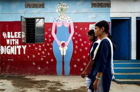 Students walk past a mural about female menstruation at Parijat Academy on the eve of Menstrual