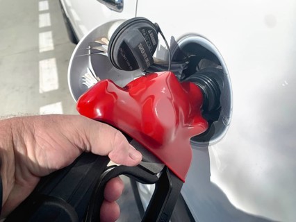 Male hand holding gas pump nossle pumping gas into vehicle