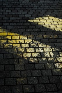 Faded yellow markings on dark, textured stone pavement create a striking contrast. The uneven