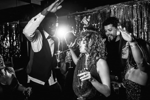 Group of stylish friends enjoying an exciting night out, dancing and sipping champagne at a lively