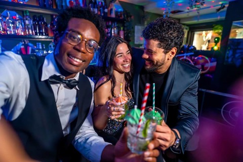 Cheerful friends raise glasses of mojitos, enjoying a vibrant night out at a trendy pub, creating
