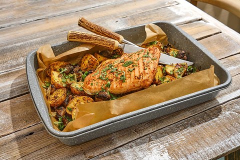 Roasted turkey breast is plated alongside an assortment of golden-brown vegetables, all garnished