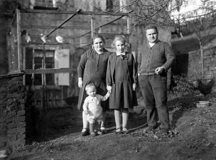Family in front of a birdcage, 1930s, Family of four standing in a rural garden area, all looking